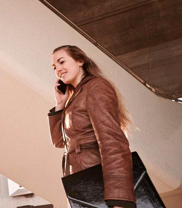En ung kvinde taler i telefon, imens hun holder en taske